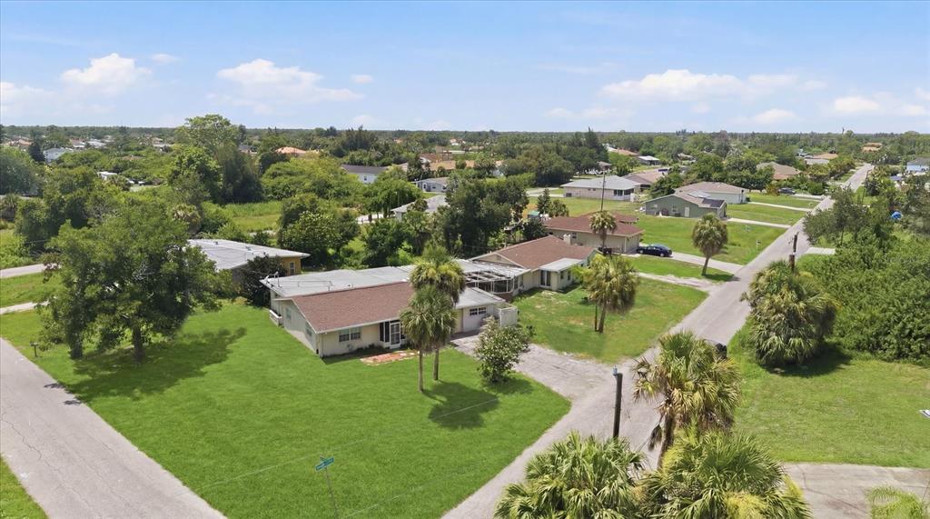 A grassy backyard features a wooden fence, mature trees, and a sunset sky — 200 ORDUNA DRIVE, NORTH PORT, FL