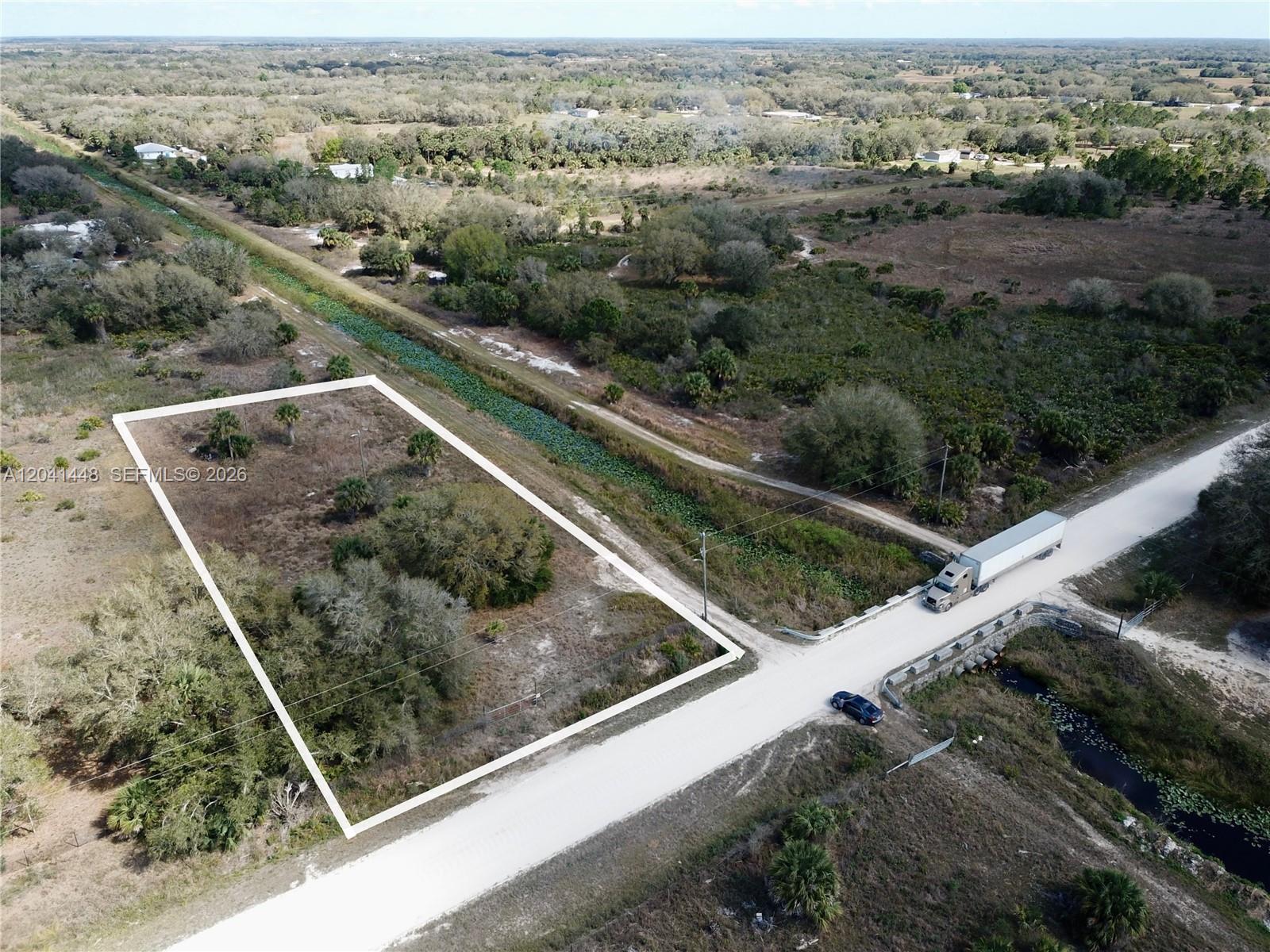An aerial view shows a rectangular vacant lot bordered by a road and a canal — 15129 NW 288th St, Okeechobee FL 34972, OKEECHOBEE, FL