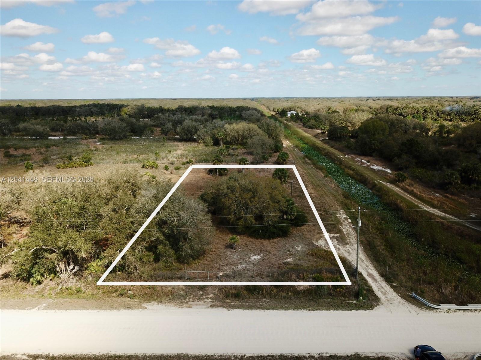 An aerial view shows a rectangular plot of land outlined in white beside a road — 15129 NW 288th St, Okeechobee FL 34972, OKEECHOBEE, FL