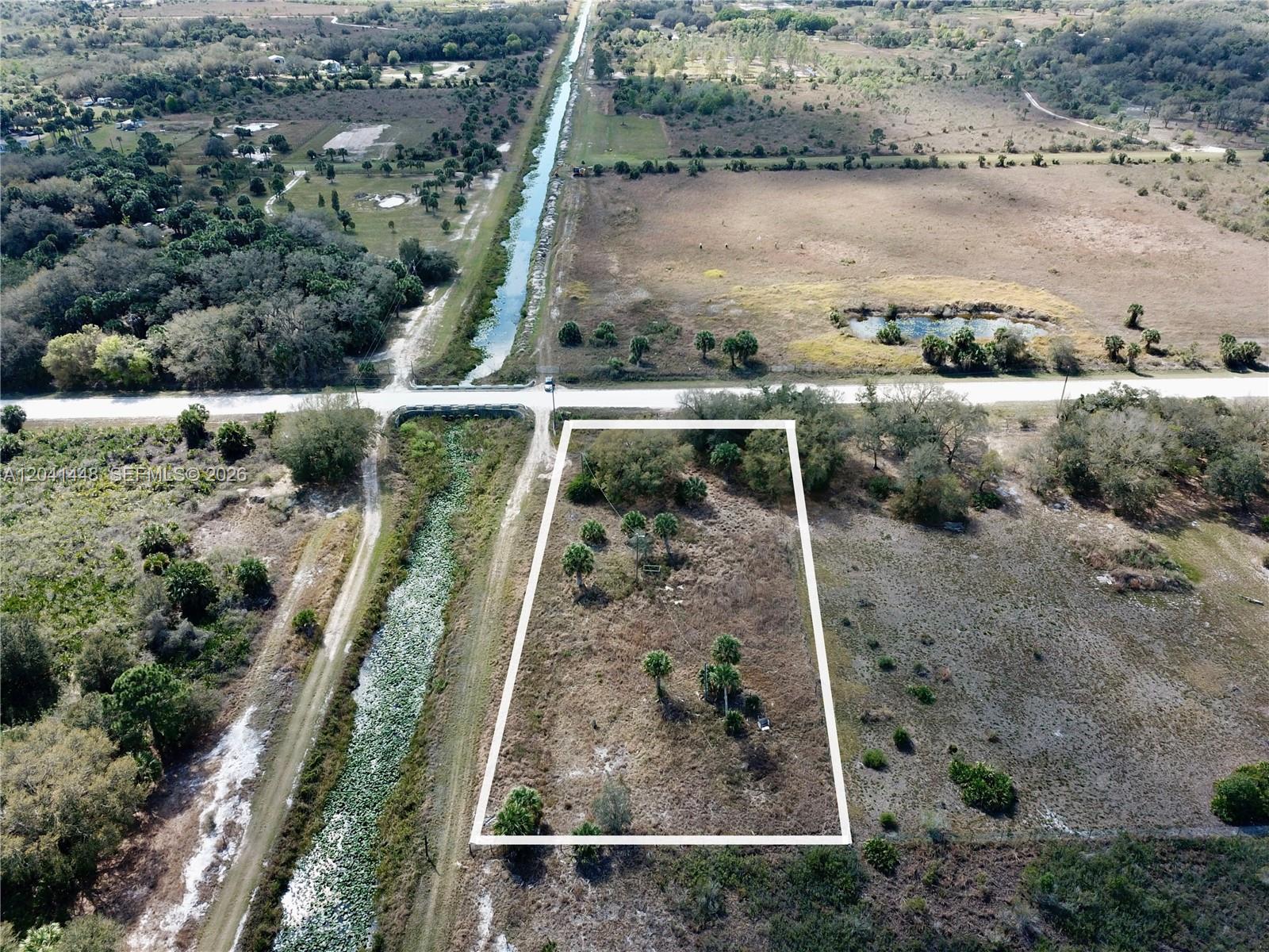 An aerial view shows a rectangular plot of land bordered by a canal and road — 15129 NW 288th St, Okeechobee FL 34972, OKEECHOBEE, FL
