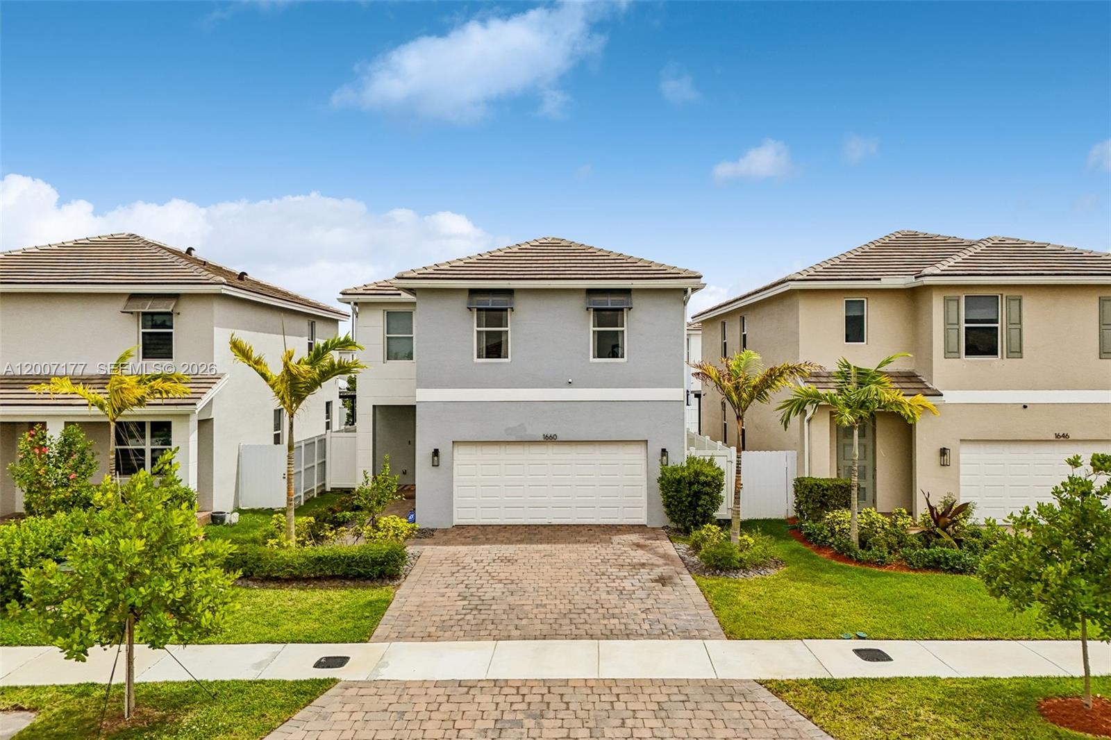 A two-story house with a paved driveway, a white garage door, and two palm trees — 1660 SE 6th St, Homestead FL 33033, HOMESTEAD, FL