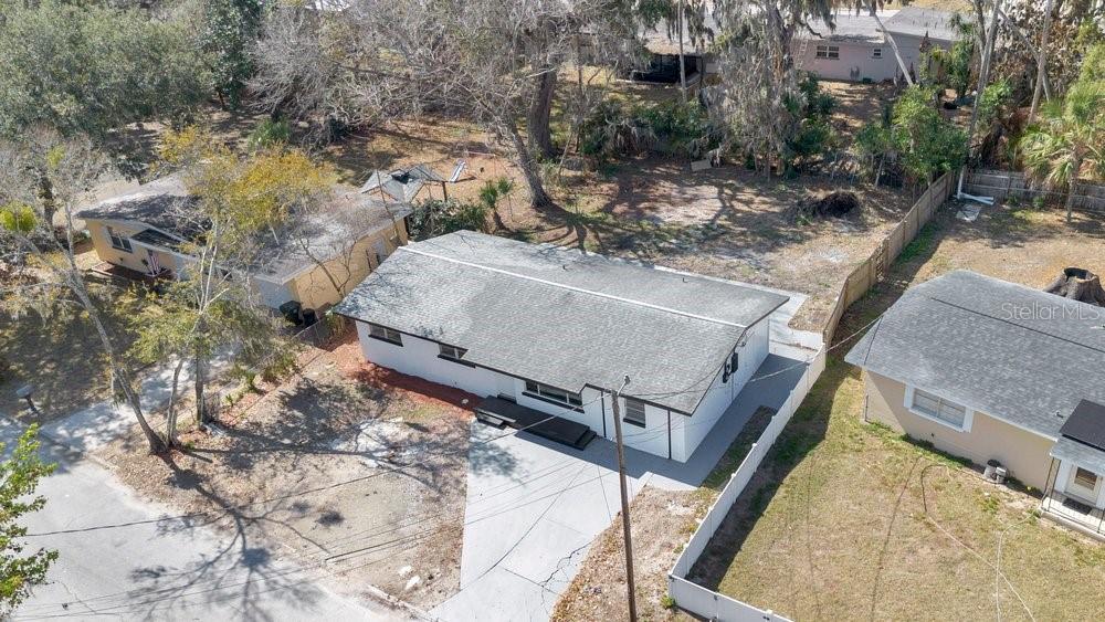 An aerial view shows a white single-story house with a gray roof and concrete driveway — 124 BAYWOOD DRIVE, DAYTONA BEACH, FL