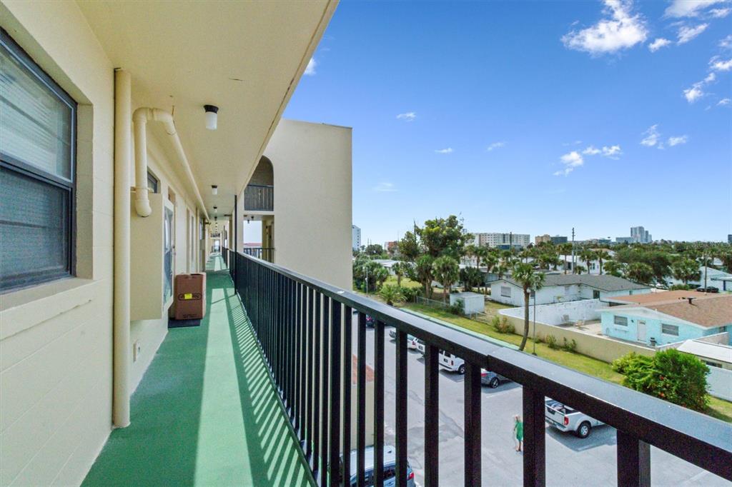 An outdoor balcony with a black metal railing overlooks a parking lot and neighborhood — 1433 N ATLANTIC AVENUE UNIT 422, DAYTONA BEACH, FL