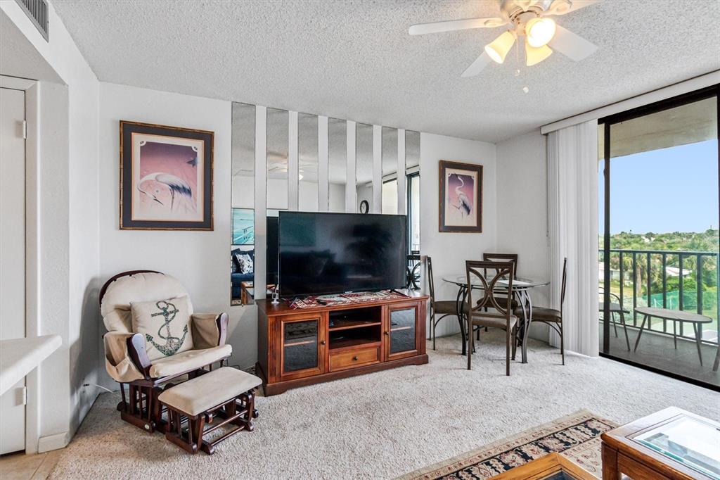 A living room features a television on a wooden stand, a rocking chair, and dining area — 1433 N ATLANTIC AVENUE UNIT 422, DAYTONA BEACH, FL