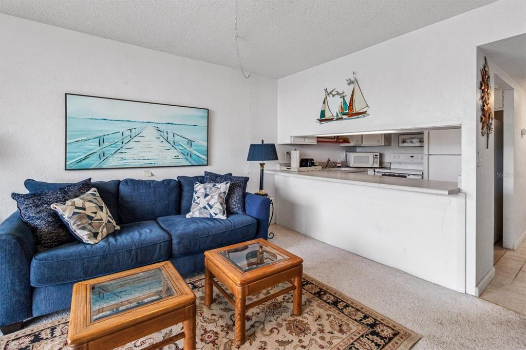 A living room features a blue sofa, two wooden coffee tables, and a kitchen pass-through — 1433 N ATLANTIC AVENUE UNIT 422, DAYTONA BEACH, FL