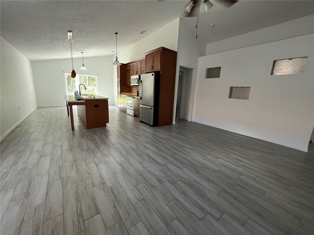 A kitchen with wood cabinets and a center island opens into a large living area — 10565 ROCKING A RUN, ORLANDO, FL