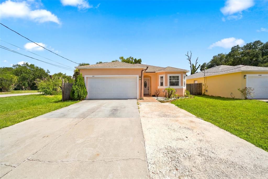 A single-story peach-colored house with a two-car garage and a concrete driveway — 4404 AMERICA STREET, ORLANDO, FL