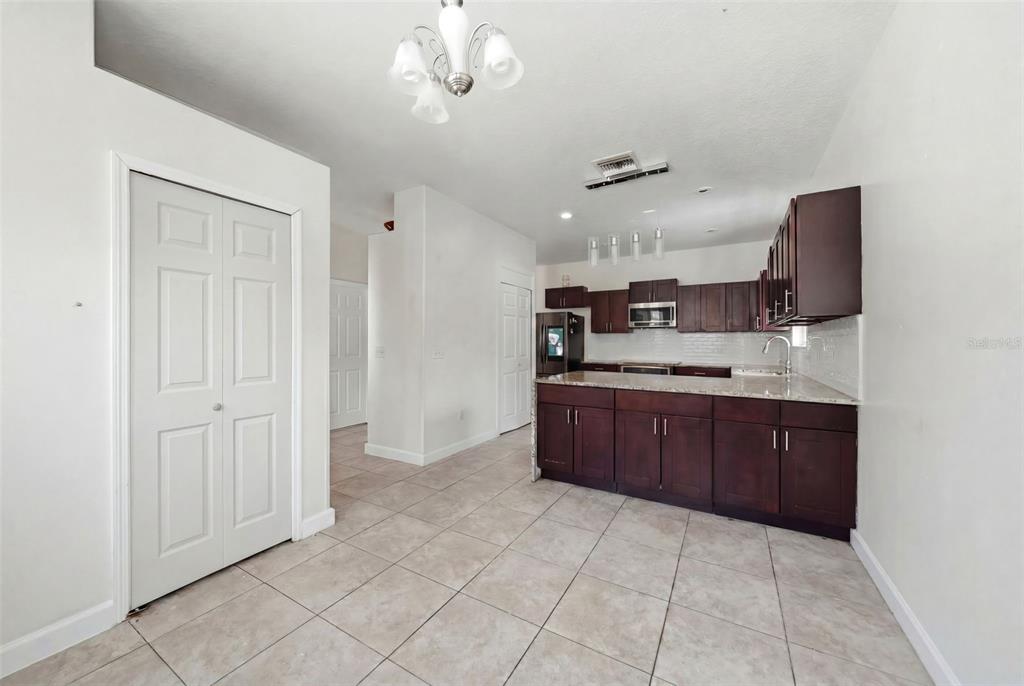 A kitchen features dark wood cabinets, granite countertops, and tile flooring in an open space — 4404 AMERICA STREET, ORLANDO, FL