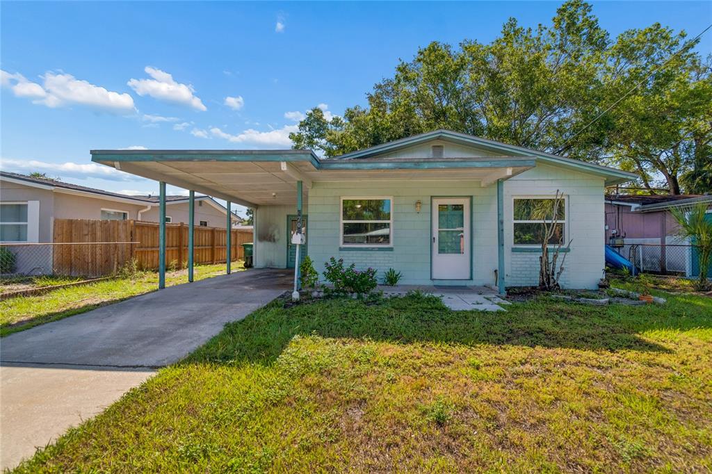 A light green single-story house features a concrete carport and a front-facing entrance — 6706 S MASCOTTE STREET, TAMPA, FL
