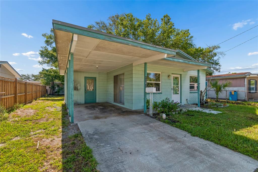 A light green house with a concrete driveway and an attached carport under a blue sky — 6706 S MASCOTTE STREET, TAMPA, FL