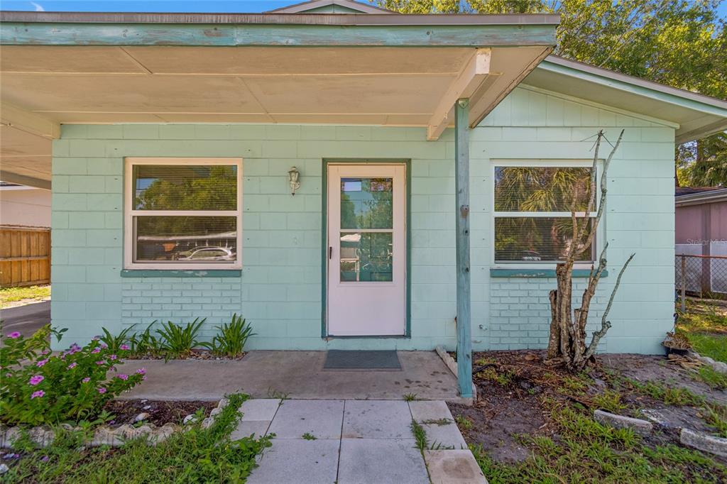 A light green concrete block house exterior with a covered porch and a white front door — 6706 S MASCOTTE STREET, TAMPA, FL
