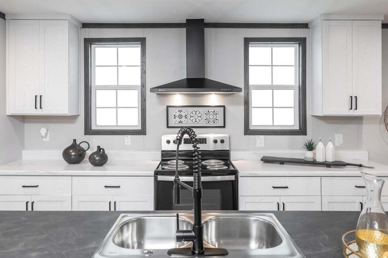 A kitchen features white cabinets, a black range hood, a stainless steel sink, and countertops — 19520 NW 260th Street, Okeechobee FL 34972, OKEECHOBEE, FL