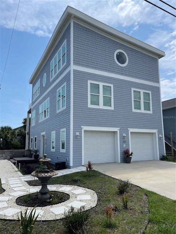 A three-story blue house with two garage doors and a circular window on the top level — 1501 S CENTRAL AVENUE, FLAGLER BEACH, FL