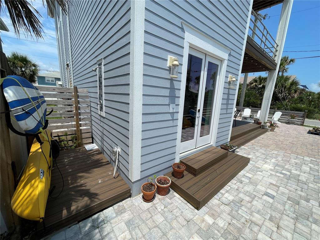 The exterior of a light blue house features a wooden deck, outdoor shower, and patio — 1501 S CENTRAL AVENUE, FLAGLER BEACH, FL