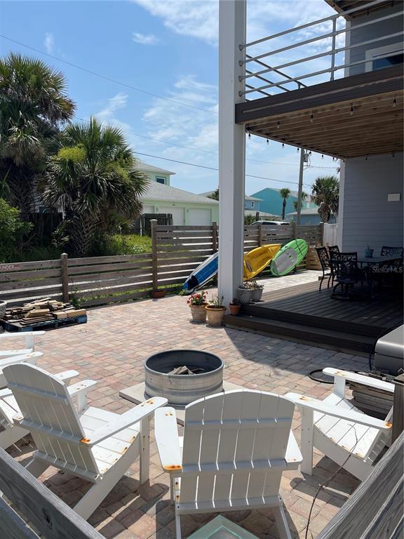 A paved patio features a fire pit, Adirondack chairs, and a wooden deck with seating — 1501 S CENTRAL AVENUE, FLAGLER BEACH, FL