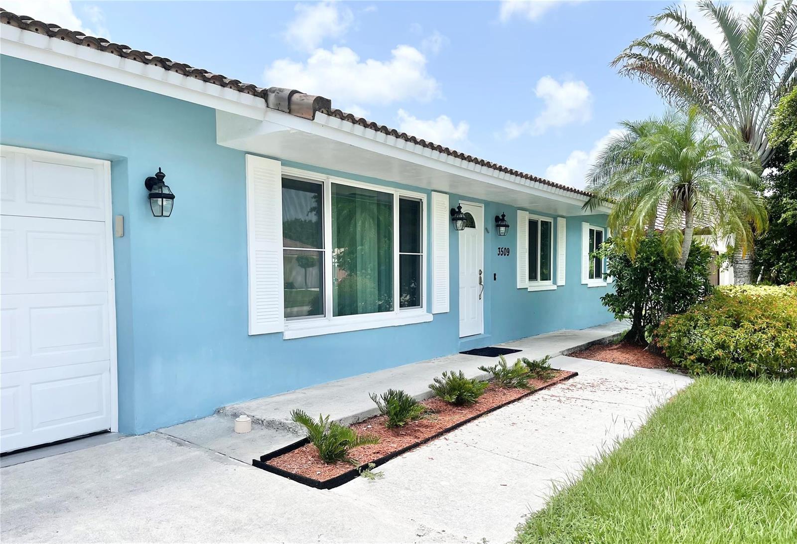 A light blue single-story house features a white front door, shutters, and a palm tree — 3509 NW 25th Way, Boca Raton FL 33434, BOCA RATON, FL