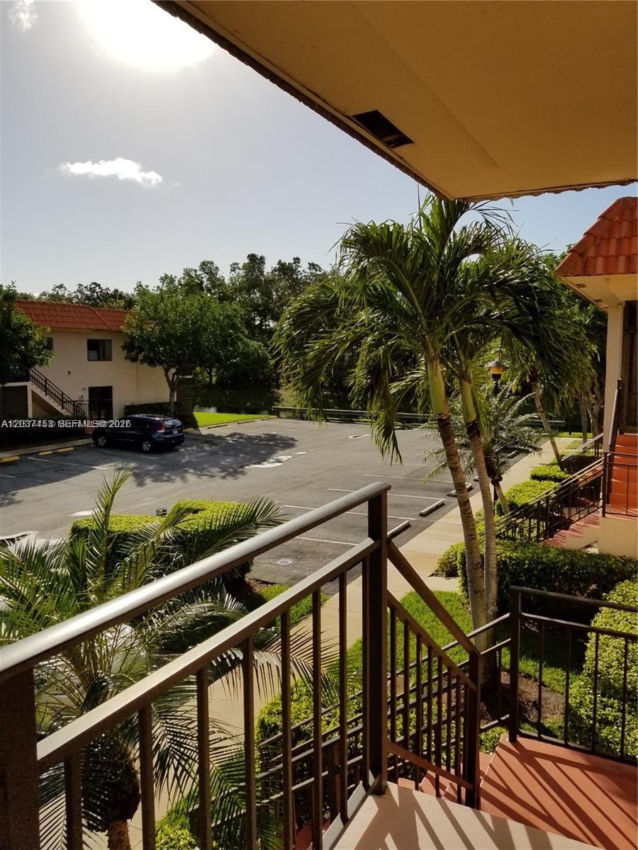 An elevated balcony view overlooks a parking lot, palm trees, and a small pond — 369 Lakeview Dr # 204, Weston FL 33326, WESTON, FL