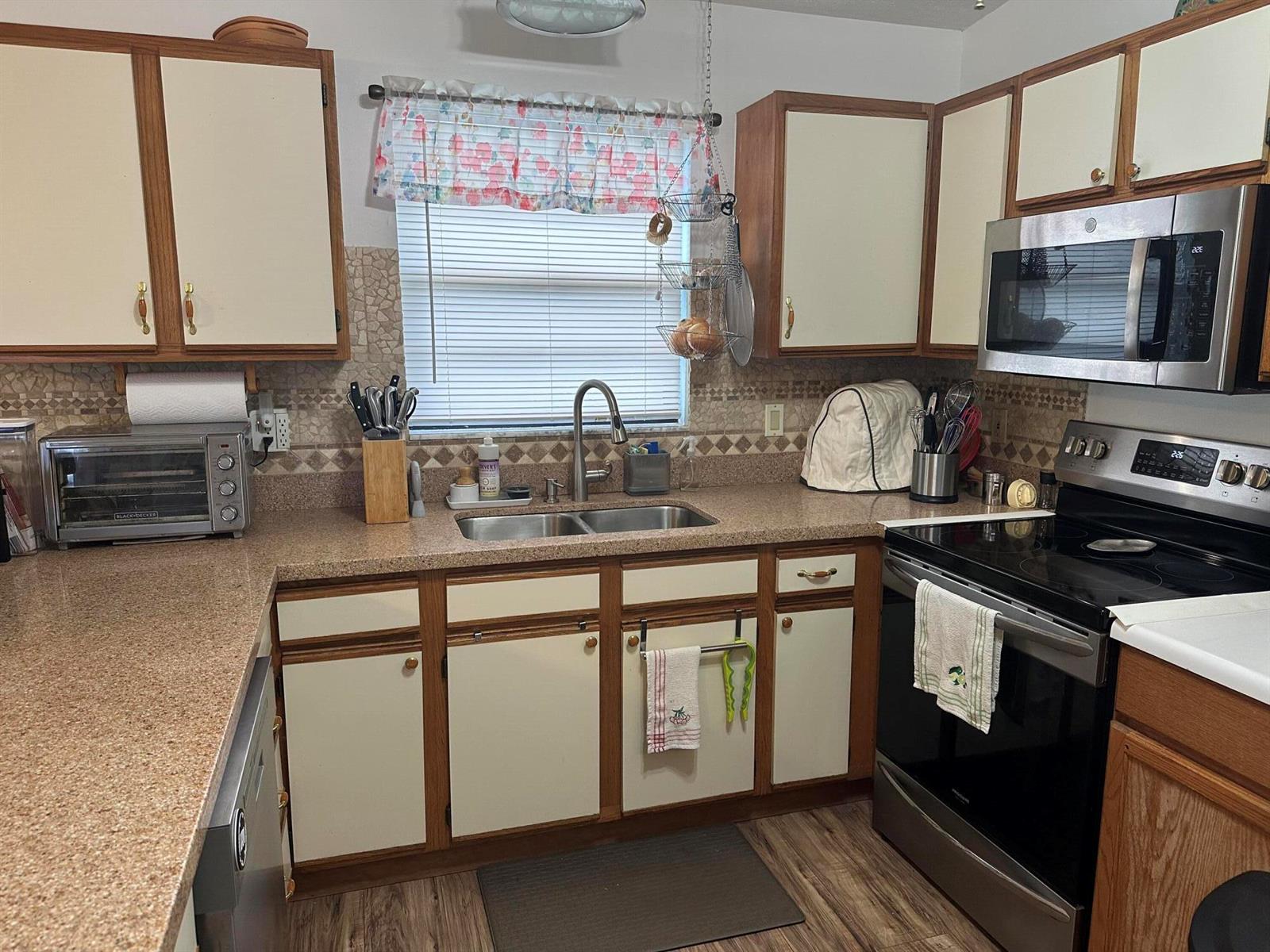 A kitchen features wood-trimmed cabinets, a stainless steel microwave, and a double-basin sink — 1110 3rd Street, Okeechobee FL 34974, OKEECHOBEE, FL