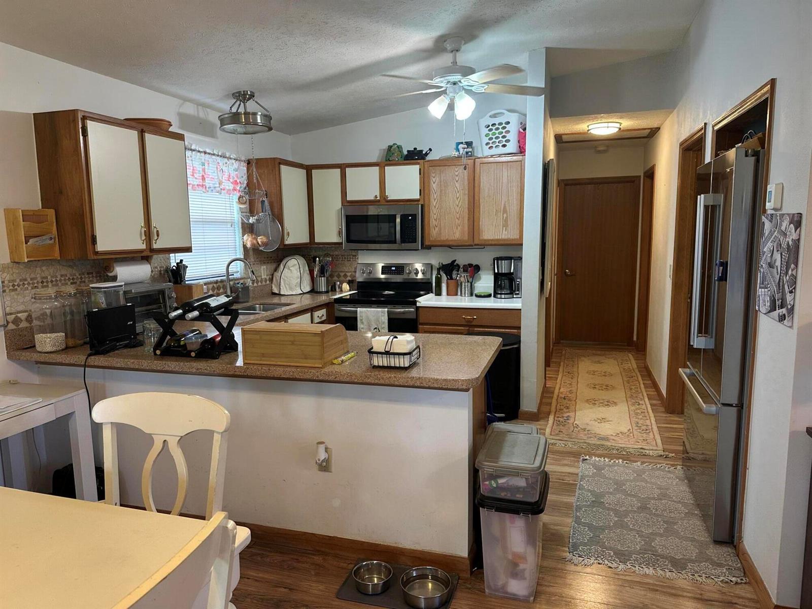 A kitchen features wood-trimmed cabinets, a peninsula countertop, stainless steel appliances, and wood-look flooring — 1110 3rd Street, Okeechobee FL 34974, OKEECHOBEE, FL