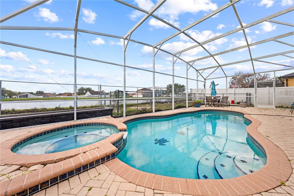 A screened-in patio features a swimming pool with an attached hot tub and paver decking — 442 TAMARIND PARKE LANE, KISSIMMEE, FL