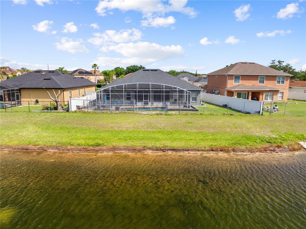 An aerial view of a house with a screened-in pool overlooking a lake — 442 TAMARIND PARKE LANE, KISSIMMEE, FL