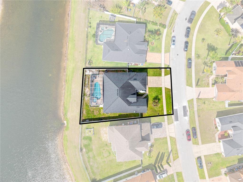 This aerial view shows a house with a pool and screened lanai beside a lake — 442 TAMARIND PARKE LANE, KISSIMMEE, FL