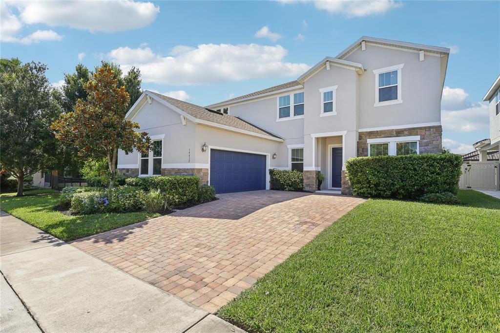 A two-story suburban house features a brick paver driveway, a blue garage door, and stone accents — 14612 GLADE HILL PARK WAY, WINTER GARDEN, FL