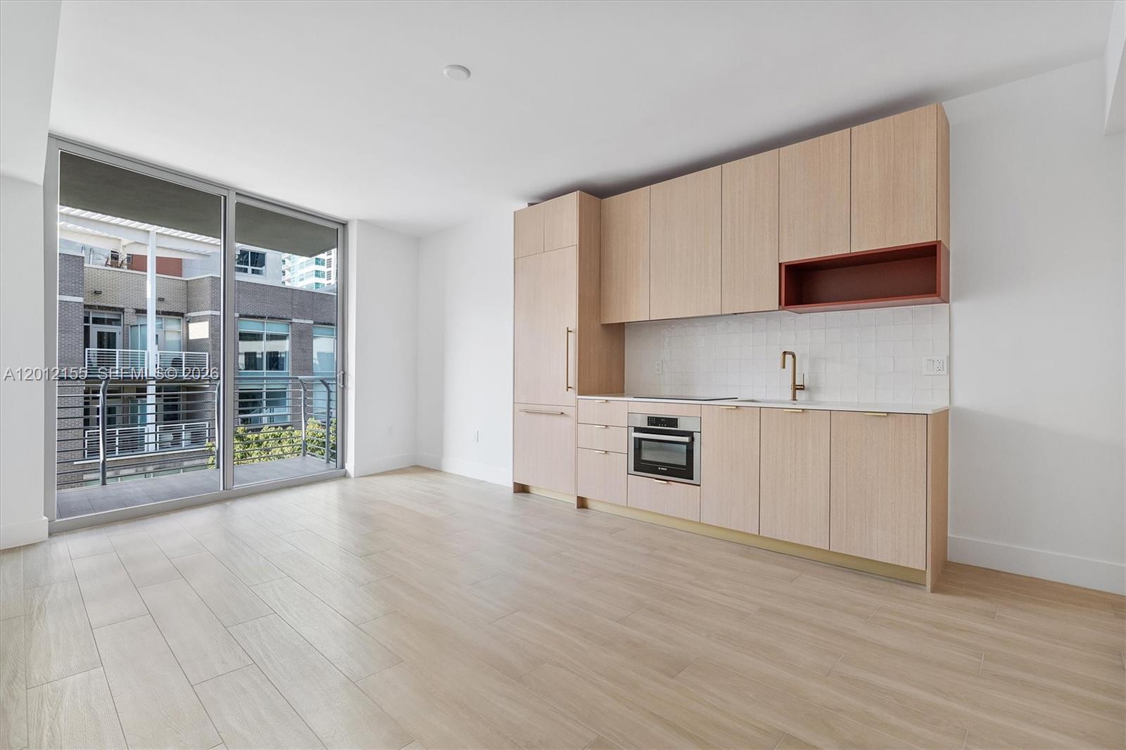 A modern kitchen with light wood cabinetry and a balcony is visible in this room — 90 NE 32 St # 413, Miami FL 33127, MIAMI, FL