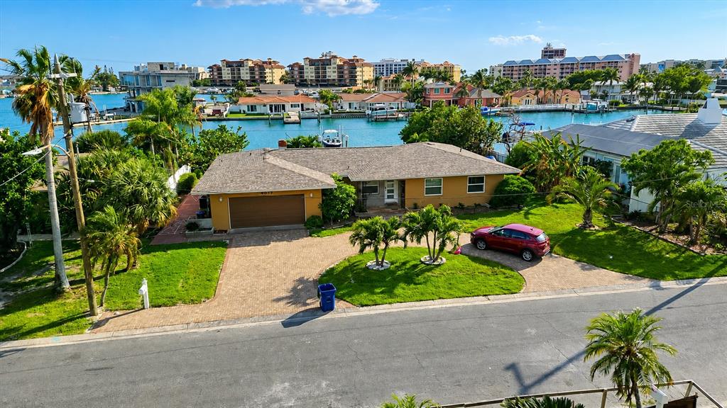 A single-story yellow house with a shingled roof and a curved driveway under a blue sky — 5412 LEILANI DRIVE, ST PETE BEACH, FL
