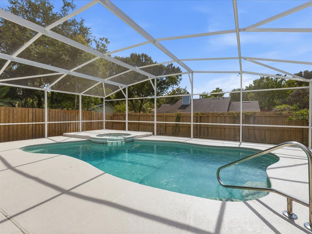A swimming pool and attached hot tub are enclosed within a screened-in patio area — 505 LAKE CHARM DRIVE, OVIEDO, FL