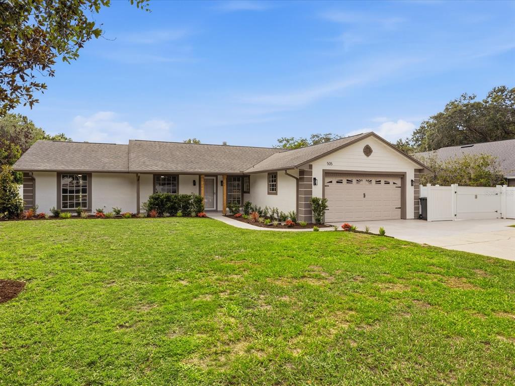 A single-story house with a beige exterior, a two-car garage, and a large front lawn — 505 LAKE CHARM DRIVE, OVIEDO, FL