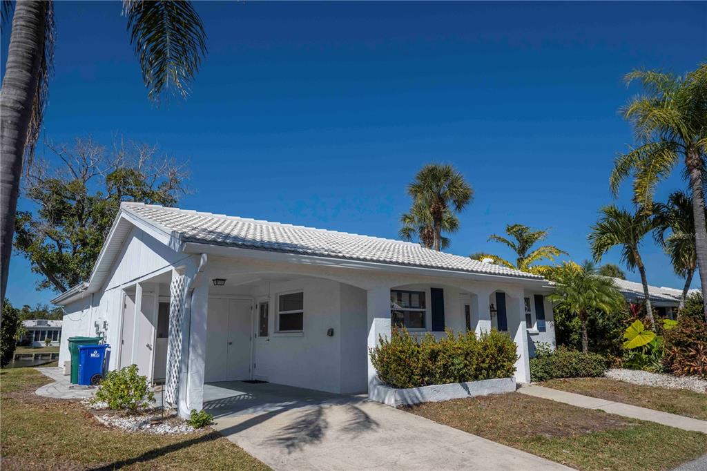 A white single-story house with a carport, tiled roof, and palm trees under a blue sky — 563 SPANISH DRIVE S, LONGBOAT KEY, FL