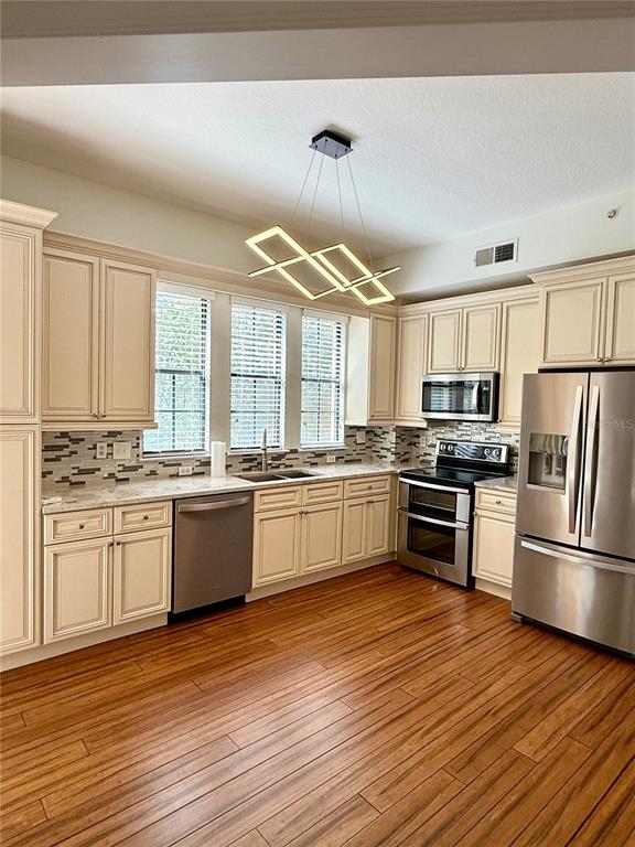 A kitchen features cream-colored cabinets, stainless steel appliances, and wood-look flooring — 501 MIRASOL CIRCLE UNIT 301, CELEBRATION, FL