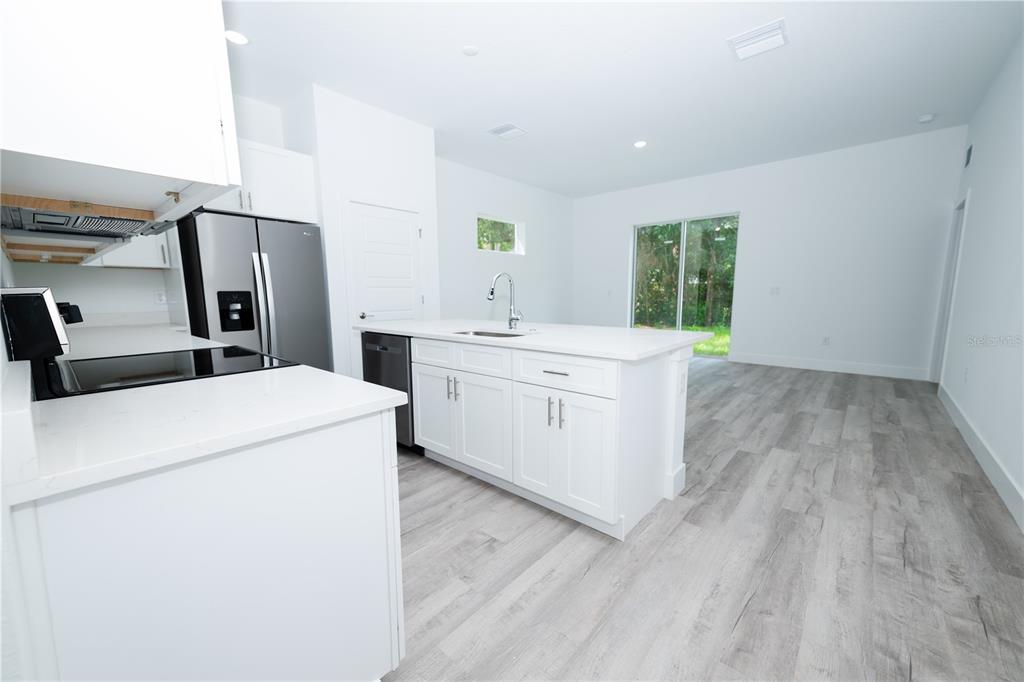 A modern kitchen features white cabinets, stainless steel appliances, and light wood-look flooring — 9298 N MENDOZA WAY, CITRUS SPRINGS, FL
