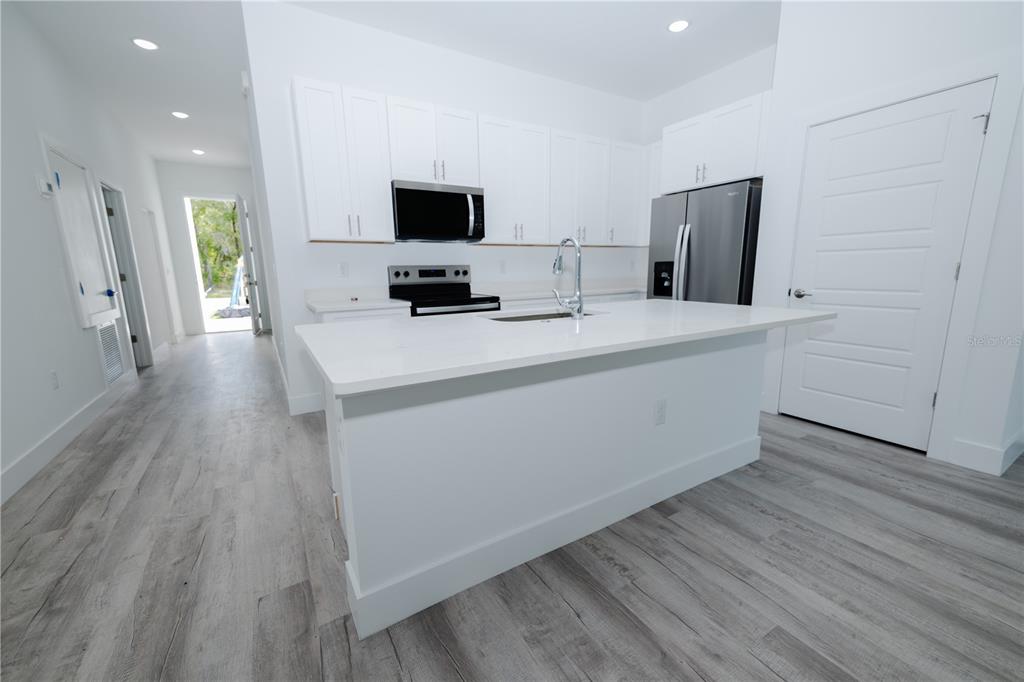 A modern kitchen features white cabinets, stainless steel appliances, and a large white island — 9298 N MENDOZA WAY, CITRUS SPRINGS, FL