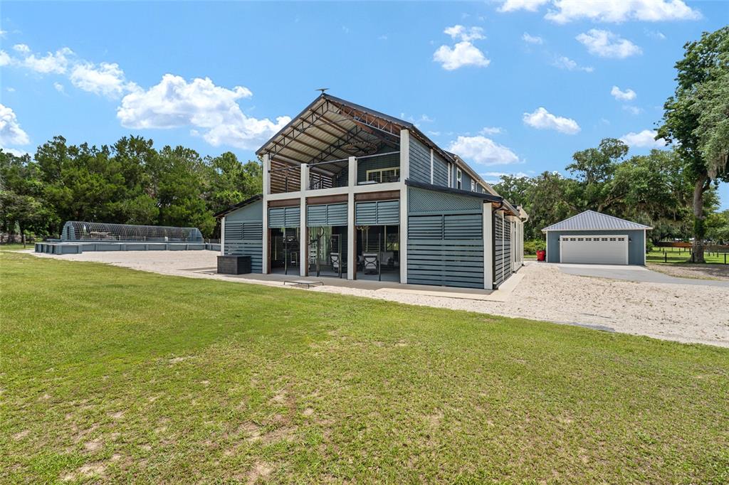 A two-story barn-style house with a metal roof, open-air balcony, and detached garage — 904 NW 111TH LANE, OXFORD, FL