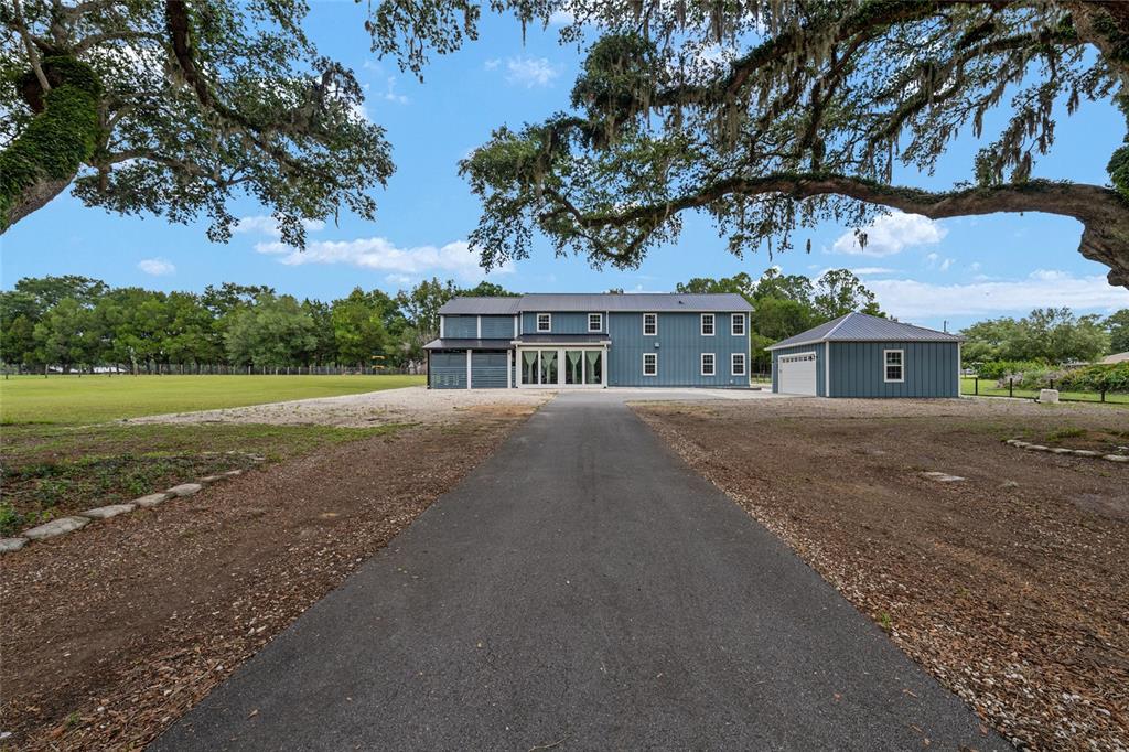 A blue two-story house and detached garage sit at the end of a paved driveway — 904 NW 111TH LANE, OXFORD, FL