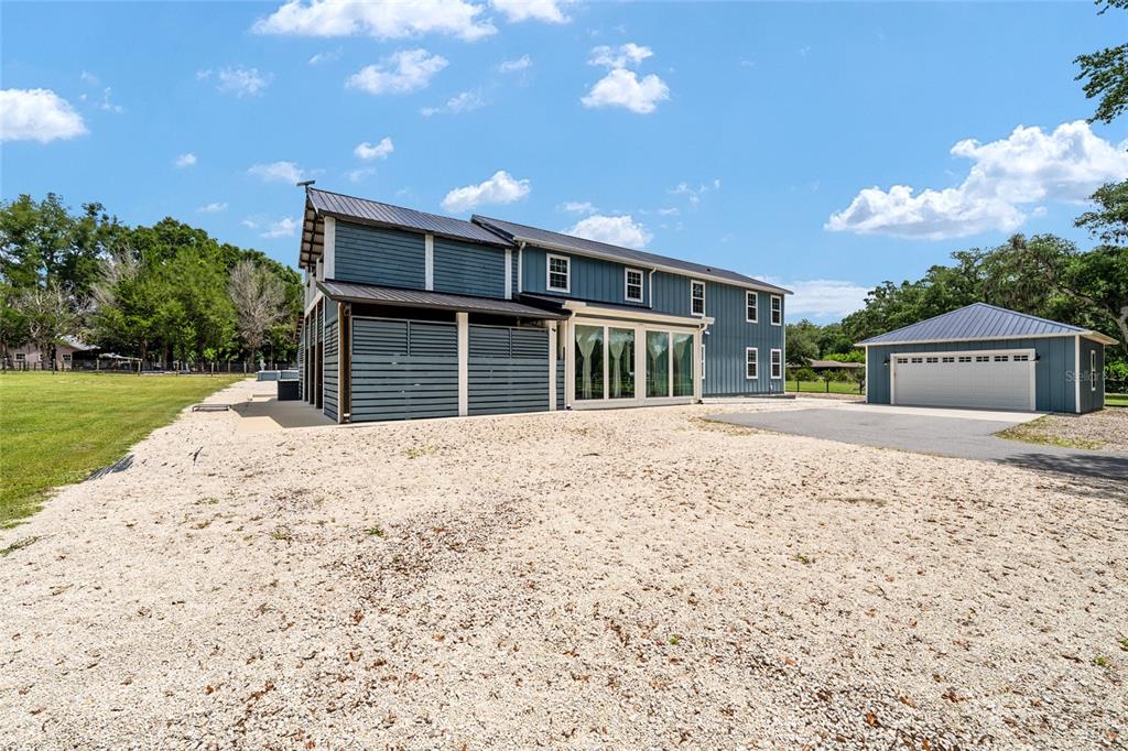 A blue two-story house with a metal roof stands next to a detached garage — 904 NW 111TH LANE, OXFORD, FL