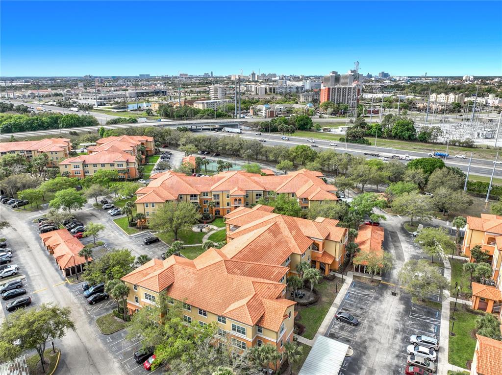 An aerial view shows multi-story apartment buildings with orange tile roofs and surrounding parking lots — 5471 VINELAND ROAD UNIT 7109, ORLANDO, FL