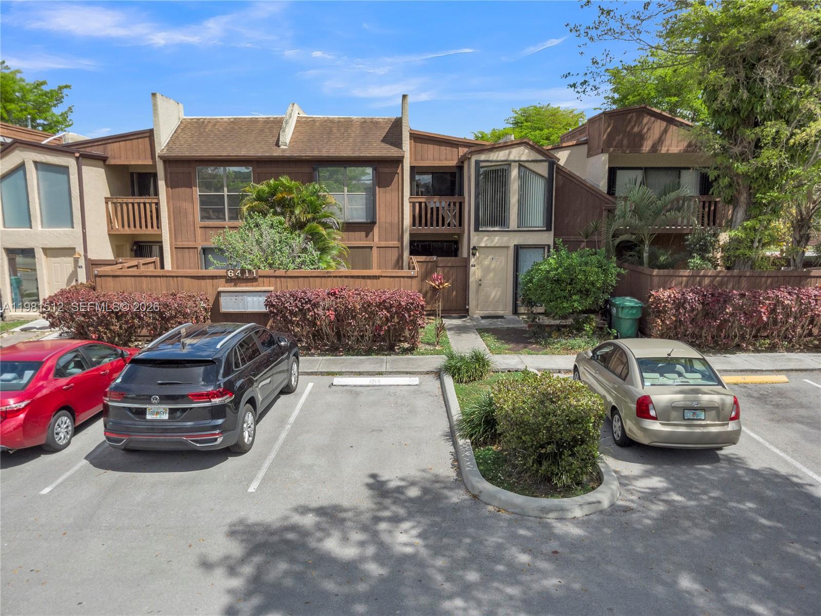 An exterior view of a two-story townhouse complex with a parking lot in front — 6411 SW 116th Ct, Miami FL 33173, MIAMI, FL