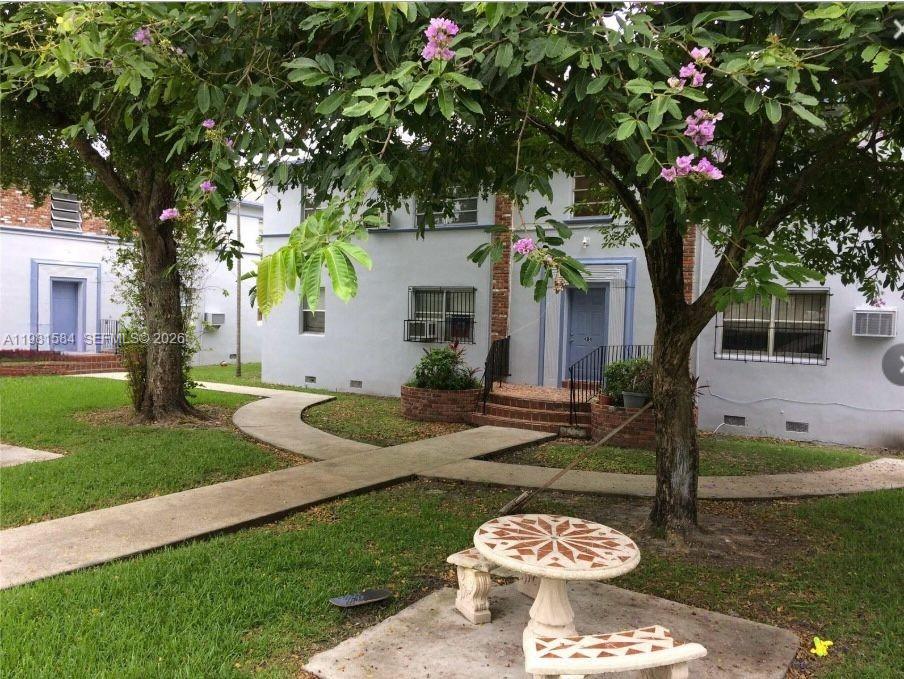 A two-story apartment building with a concrete walkway, lawn, and a stone table set — 424 NE 82nd St # 4C, Miami FL 33138, MIAMI, FL