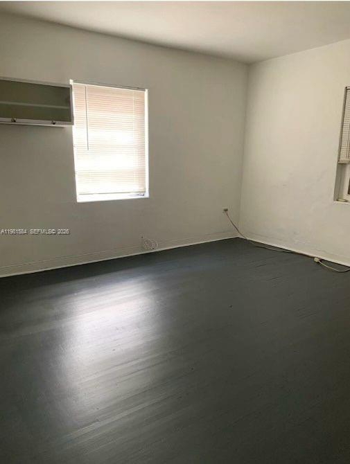 An empty room features dark painted wood floors, white walls, and a window with blinds — 424 NE 82nd St # 4C, Miami FL 33138, MIAMI, FL