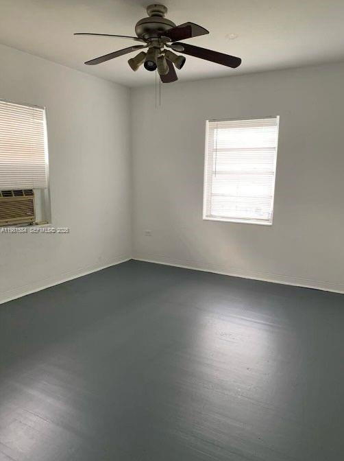 An empty room with gray painted floors, white walls, a ceiling fan, and two windows — 424 NE 82nd St # 4C, Miami FL 33138, MIAMI, FL