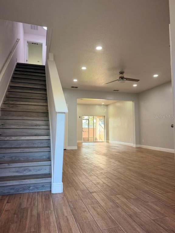 An interior view shows a staircase with wood-look steps leading to a bright, open-concept living area — 2962 RODRICK CIRCLE, ORLANDO, FL