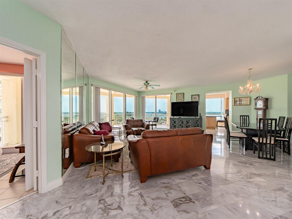 A living and dining area features light green walls, marble floors, and leather furniture — 1180 GULF BOULEVARD UNIT 906, CLEARWATER BEACH, FL