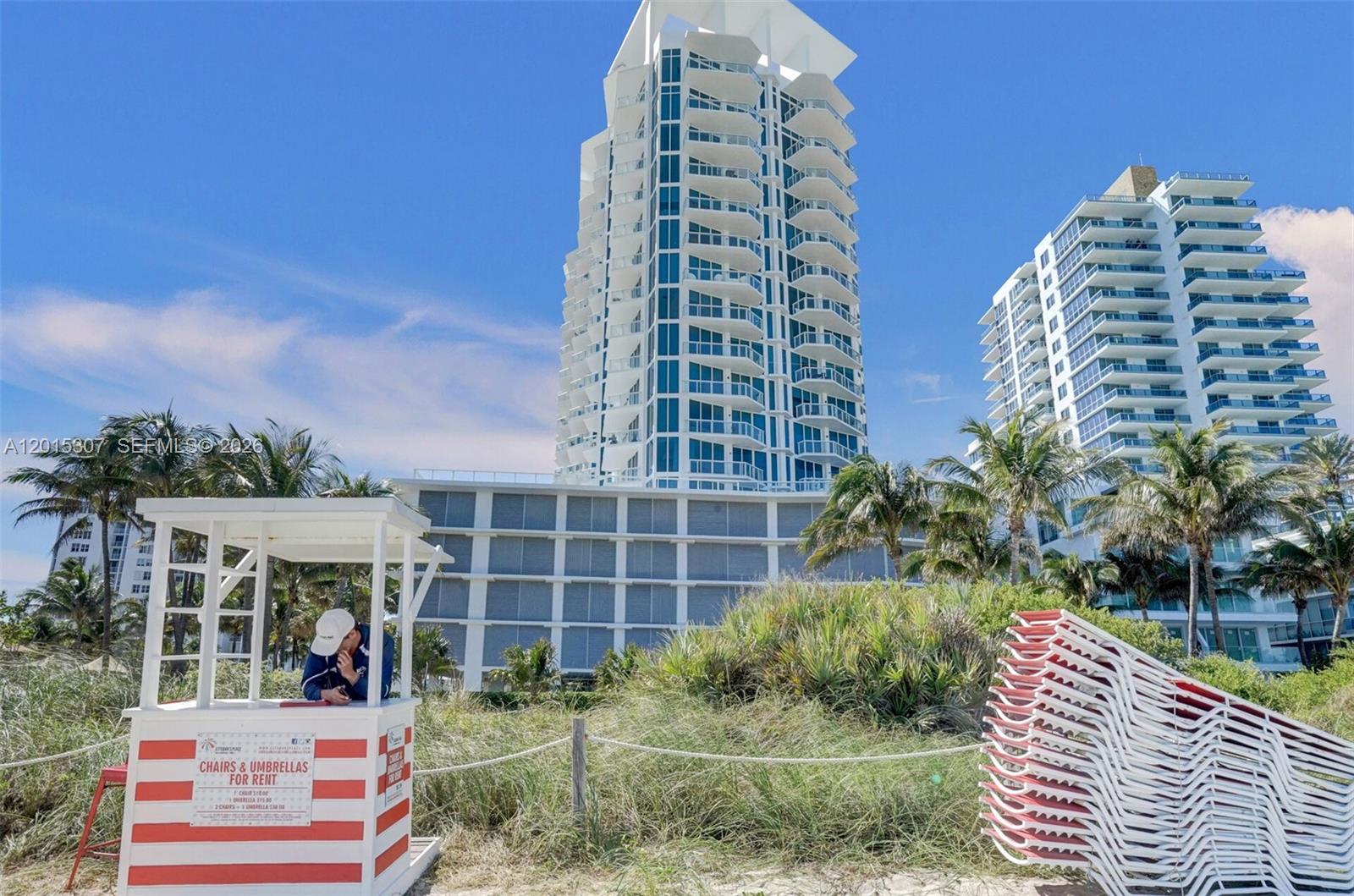 A beach rental stand sits in front of tall residential towers and palm trees — 6515 Collins Ave # 1107, Miami Beach FL 33141, MIAMI BEACH, FL