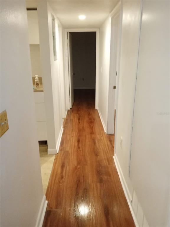 A narrow hallway features wood-look flooring, white walls, and doorways leading to other rooms — 3242 SEMORAN BOULEVARD UNIT 25, ORLANDO, FL