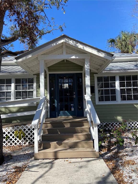 A front view of a house with a covered porch, wooden stairs, and green siding — 1267 2ND STREET, SARASOTA, FL