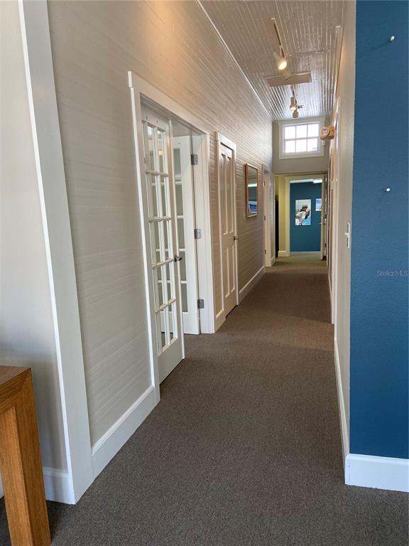A long hallway features carpeted flooring, white paneled walls, and a white beadboard ceiling — 1267 2ND STREET, SARASOTA, FL
