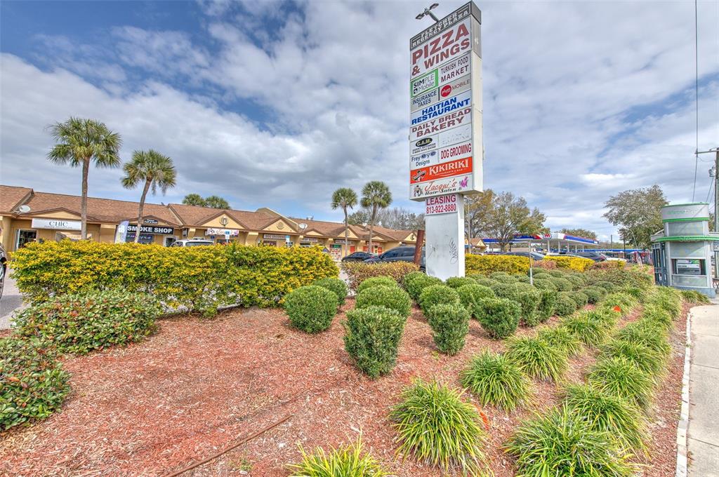 A tall sign lists various businesses in front of a single-story commercial strip mall — 1402 E FLETCHER AVENUE UNIT 1406, TAMPA, FL